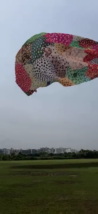 カラフルな点描作品が荒川河川敷の空を横切るAR画面
